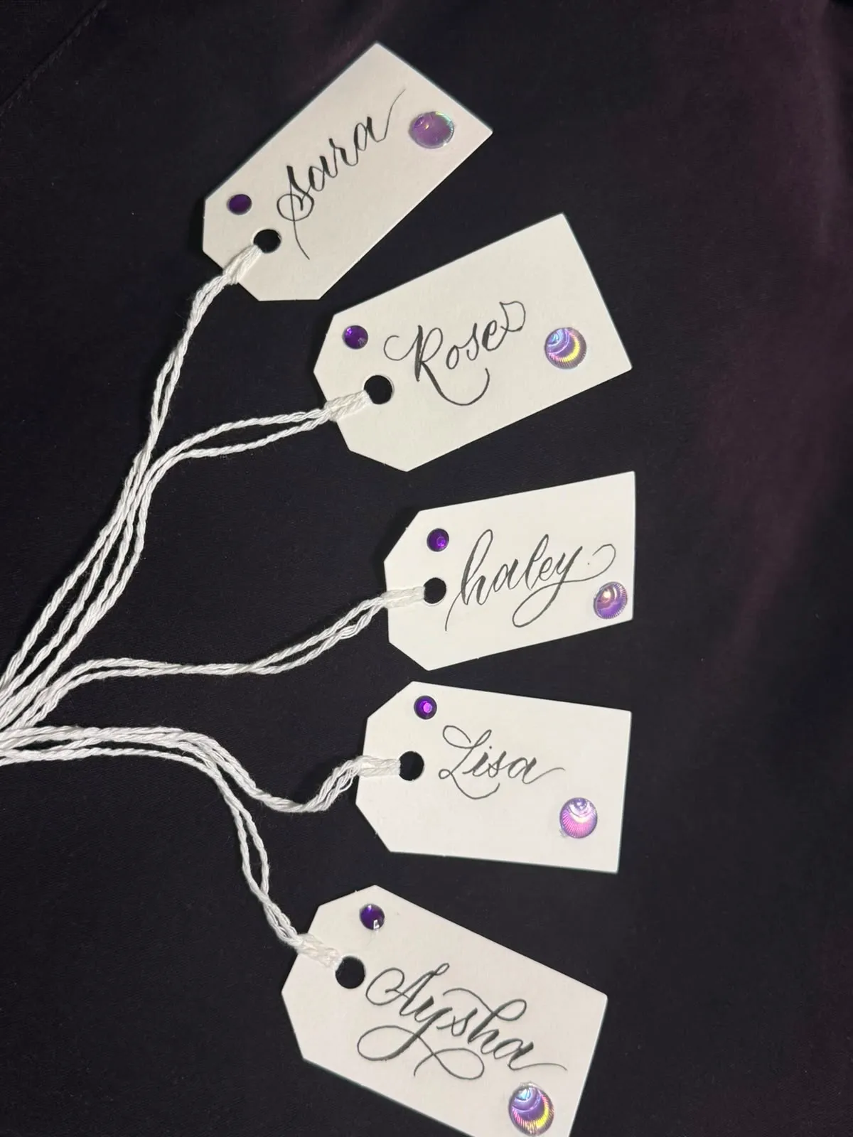 White name tags with sequins lettered in delicate modern calligraphy