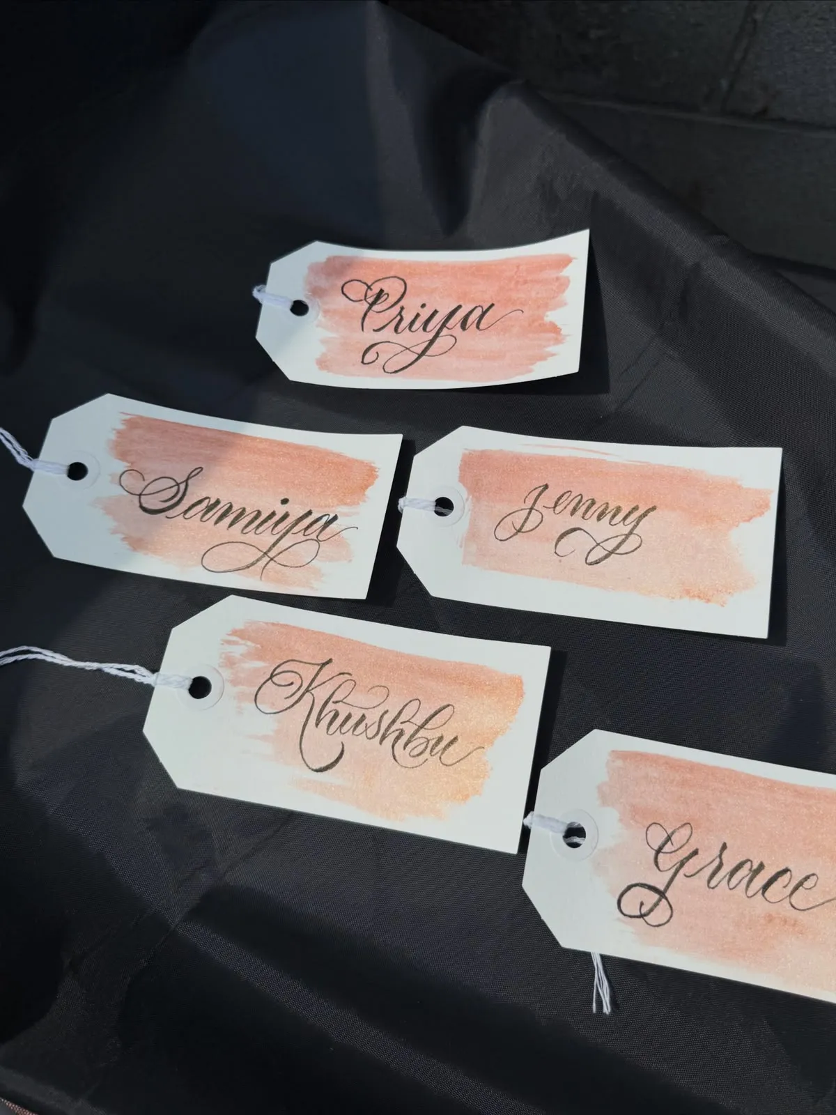 Peach watercolour place-card tags with names in modern calligraphy